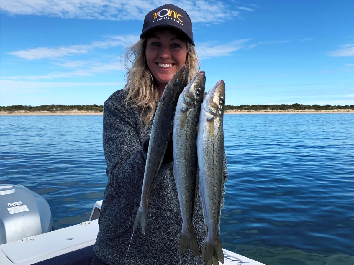 Angler holding up a fresh catch of fish on the calm waters of Coffin Bay